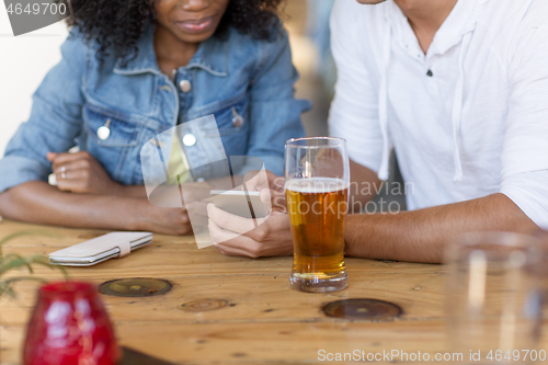 Image of couple with smartphone and beer at bar