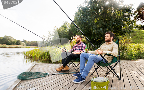 Image of male friends fishing and drinking beer on lake