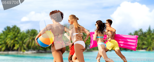 Image of friends run with beach ball and swimming mattress