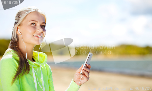Image of woman listening to music on smartphone on beach
