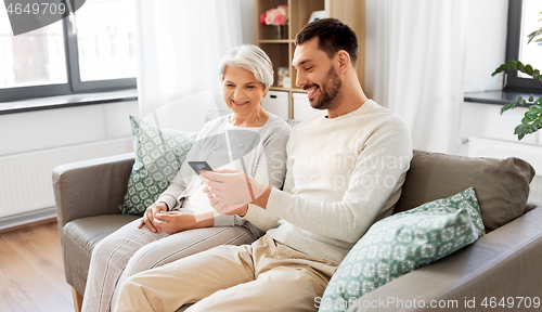 Image of old mother and adult son with smartphone at home