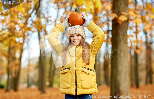 Image of happy girl with pumpkin at autumn park