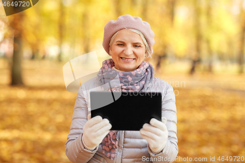 Image of senior woman with tablet computer at autumn park