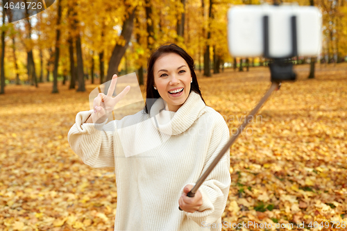 Image of woman taking selfie by smartphone at autumn park