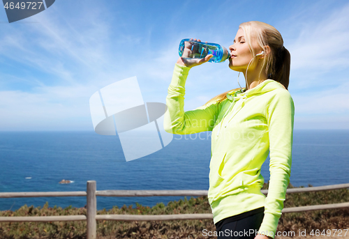 Image of woman drinking water after exercising at seaside