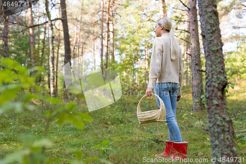 Image of young woman picking mushrooms in autumn forest