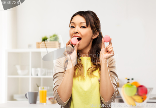 Image of happy asian woman with macarons