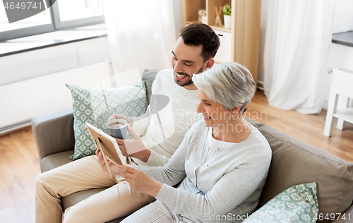 Image of adult son and senior mother with photo at home