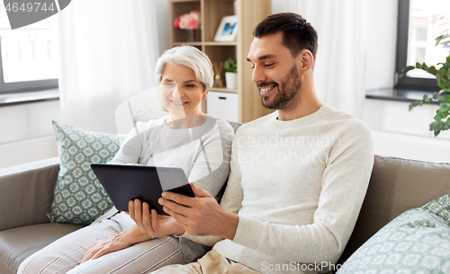 Image of old mother and adult son with tablet pc at home