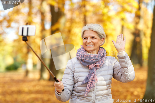 Image of senior woman taking selfie at autumn park