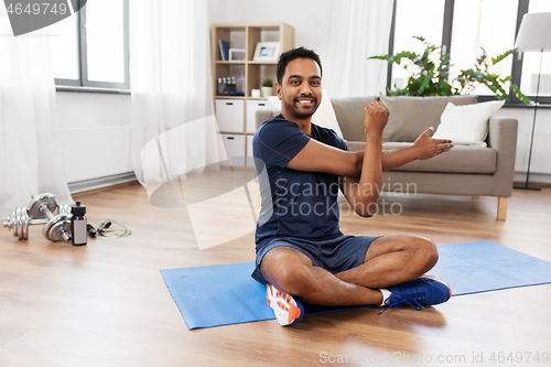 Image of man training and stretching arm at home