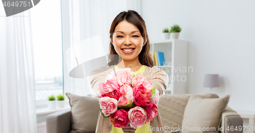 Image of happy asian woman with bunch of flowers at home