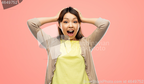 Image of happy asian woman holding to her head