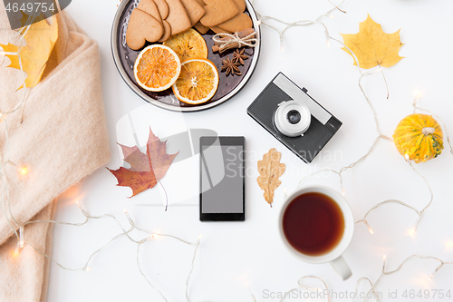 Image of smartphone, tea, camera, cookies and autumn leaves