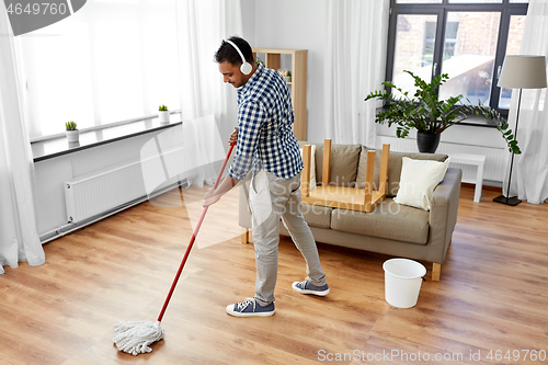 Image of man in headphones with mop cleaning floor at home