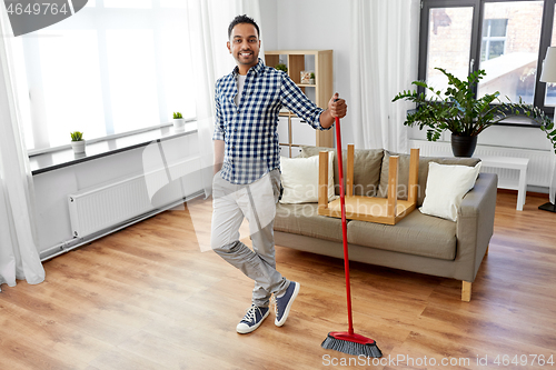 Image of man with broom cleaning floor at home