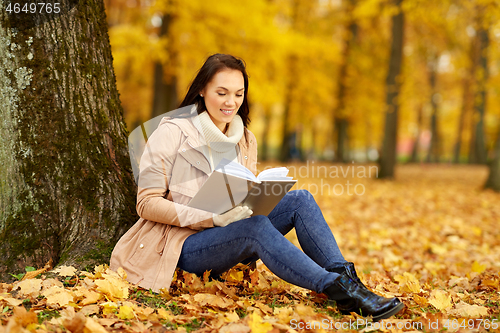 Image of woman reading book at autumn park