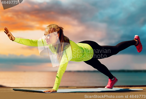 Image of woman training on exercise mat over sea sunset