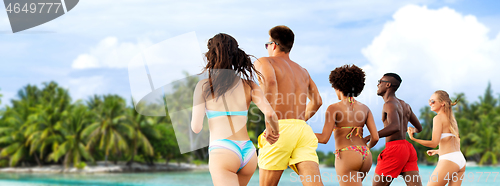 Image of happy friends running on summer beach