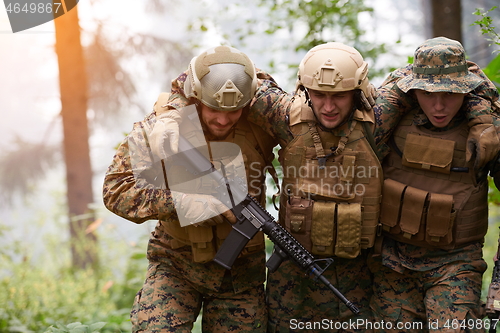 Image of military squad in action rescue wounded soldier