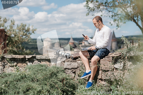 Image of Handsome businessman with laptop talking on the phone