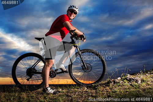 Image of Cyclist riding mountain bike on trail at evening.