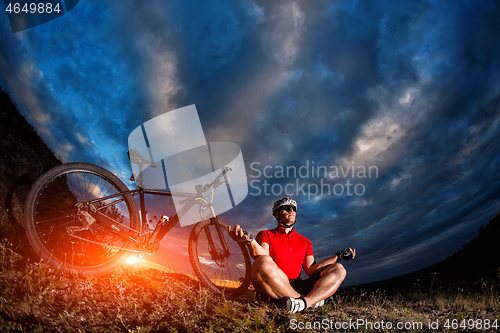 Image of Man cyclist is engaged in yoga on a sunset