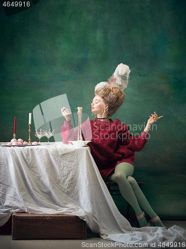 Image of Young woman as Marie Antoinette on dark background. Retro style, comparison of eras concept.