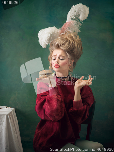 Image of Young woman as Marie Antoinette on dark background. Retro style, comparison of eras concept.