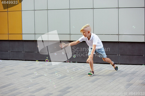 Image of Smiling boy running, playing in town, city in summer day