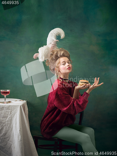 Image of Young woman as Marie Antoinette on dark background. Retro style, comparison of eras concept.