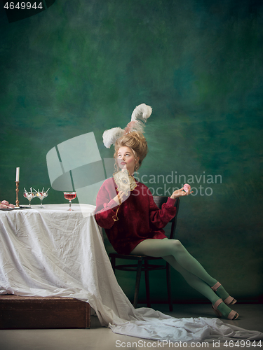 Image of Young woman as Marie Antoinette on dark background. Retro style, comparison of eras concept.