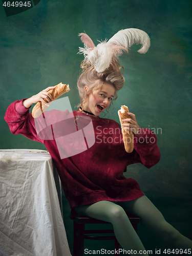 Image of Young woman as Marie Antoinette on dark background. Retro style, comparison of eras concept.