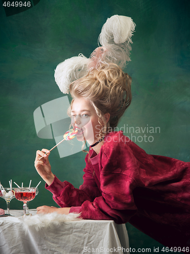 Image of Young woman as Marie Antoinette on dark background. Retro style, comparison of eras concept.