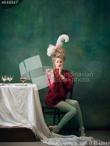 Image of Young woman as Marie Antoinette on dark background. Retro style, comparison of eras concept.