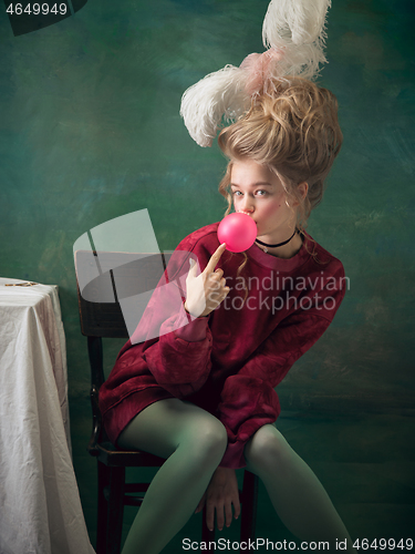 Image of Young woman as Marie Antoinette on dark background. Retro style, comparison of eras concept.