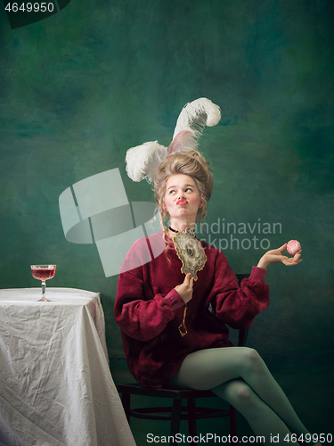 Image of Young woman as Marie Antoinette on dark background. Retro style, comparison of eras concept.