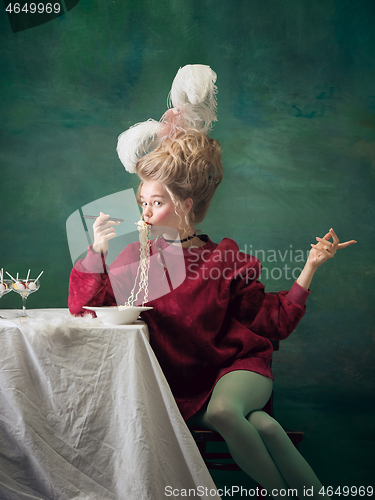 Image of Young woman as Marie Antoinette on dark background. Retro style, comparison of eras concept.