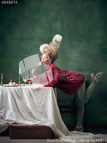 Image of Young woman as Marie Antoinette on dark background. Retro style, comparison of eras concept.