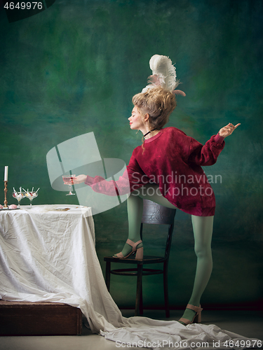 Image of Young woman as Marie Antoinette on dark background. Retro style, comparison of eras concept.