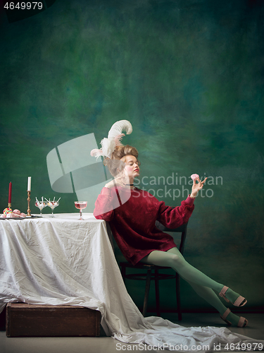 Image of Young woman as Marie Antoinette on dark background. Retro style, comparison of eras concept.