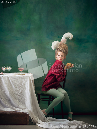 Image of Young woman as Marie Antoinette on dark background. Retro style, comparison of eras concept.