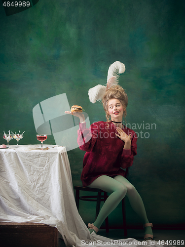 Image of Young woman as Marie Antoinette on dark background. Retro style, comparison of eras concept.