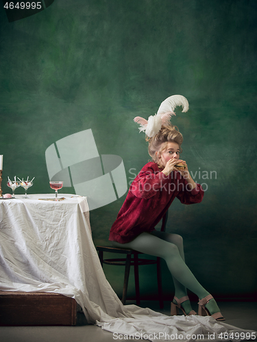 Image of Young woman as Marie Antoinette on dark background. Retro style, comparison of eras concept.