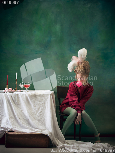 Image of Young woman as Marie Antoinette on dark background. Retro style, comparison of eras concept.
