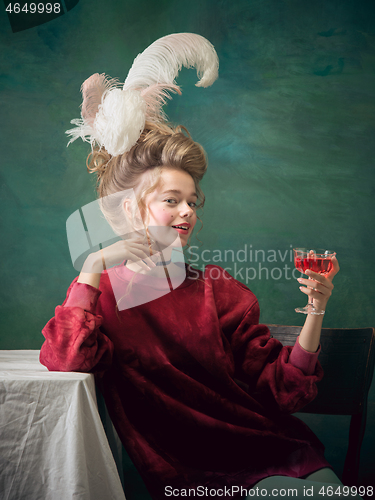 Image of Young woman as Marie Antoinette on dark background. Retro style, comparison of eras concept.