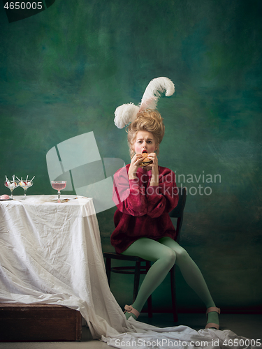 Image of Young woman as Marie Antoinette on dark background. Retro style, comparison of eras concept.