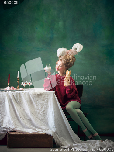 Image of Young woman as Marie Antoinette on dark background. Retro style, comparison of eras concept.