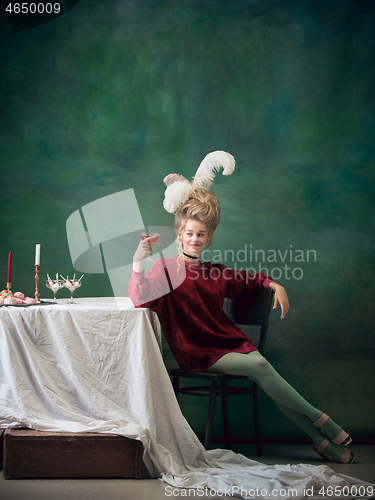 Image of Young woman as Marie Antoinette on dark background. Retro style, comparison of eras concept.