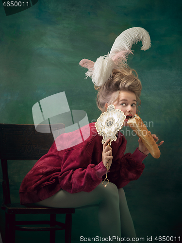 Image of Young woman as Marie Antoinette on dark background. Retro style, comparison of eras concept.